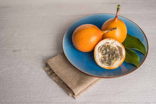 Fresh granadillas on wooden board with leaves.