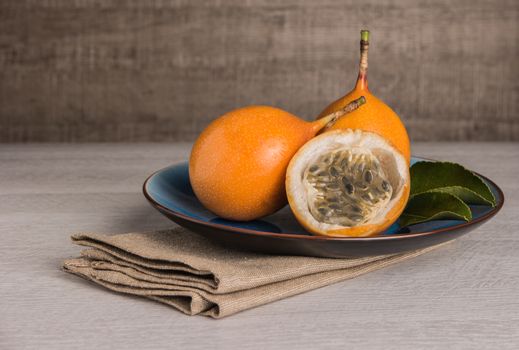 Fresh granadillas on wooden board with leaves.