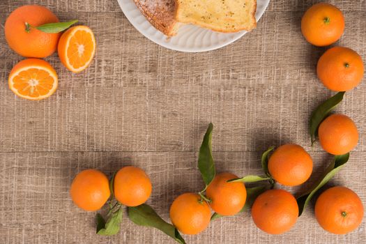 Fresh clementines and cake on wooden board with leaves. Top view with copy space.