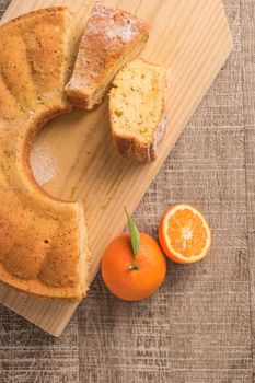 Slices of clementine cake with powdered sugar topping. Cake on a board with fresh clementines on wooden board.