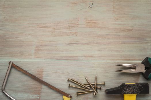 Set of saw, plier, screw and hammer. Tools over a wood panel. Top view with copy space.