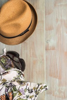 Travel, summer vacation, tourism and objects concept - close up of hat, wallet, sunglasses and scarf on wooden table. Top view with copy space.