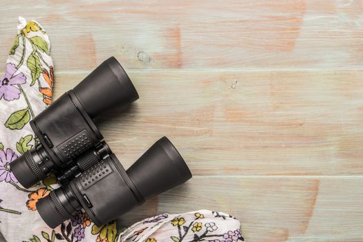 Travel, summer vacation, tourism and objects concept - close up binoculars and scarf on wooden table. Top view with copy space.