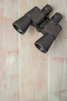 Binoculars on a natural blue wood surface. Top view with copy space.