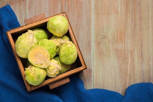 Fresh brussel sprouts over rustic wooden texture. Top view with copy space.