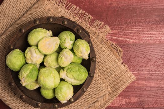 Fresh brussel sprouts over rustic wooden texture. Top view with copy space.