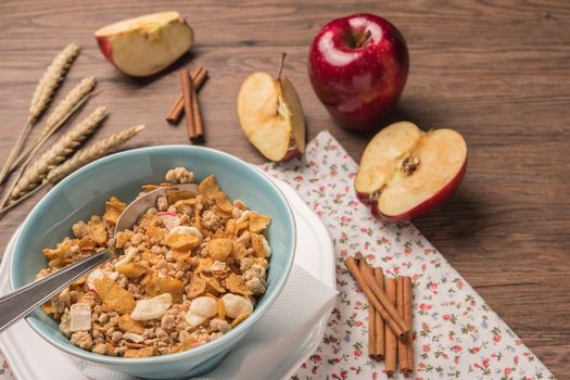 Healthy breakfast with muesli, red apple and cinnamon on rustic wooden table. Top view with copy space.