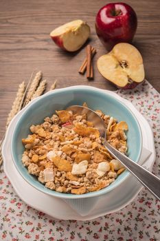 Healthy breakfast with muesli, red apple and cinnamon on rustic wooden table. Top view with copy space.