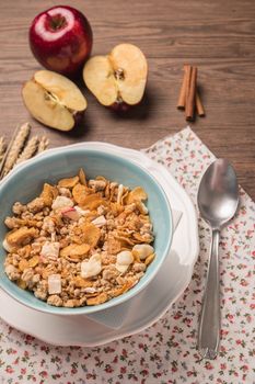 Healthy breakfast with muesli, red apple and cinnamon on rustic wooden table. Top view with copy space.