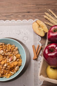 Healthy breakfast with muesli, red apple and cinnamon on rustic wooden table. Top view with copy space.