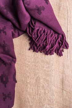 Woolen soft and worm scarf on rustic wooden background. Top view with copy space