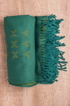 Woolen soft and worm scarf on rustic wooden background. Top view with copy space