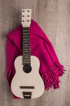 Guitar and blanket on rustic wooden background texture. Top view with copy space