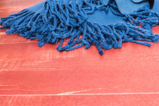 Woolen soft and worm scarf on rustic wooden background. Top view with copy space