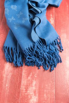 Woolen soft and worm scarf on rustic wooden background. Top view with copy space
