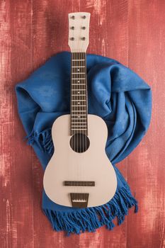 Guitar and blanket on rustic wooden background texture. Top view with copy space