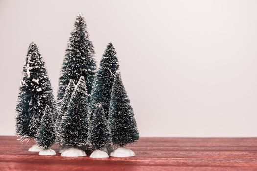 Miniature evergreen trees on rustic red colored wooden board