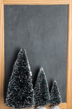 Blank rustic Christmas chalkboard slate with christmas trees ready for your seasonal greetings. Top view with copy space 