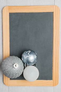 Blank rustic Christmas chalkboard slate with balls ready for your seasonal greetings. Top view with copy space 