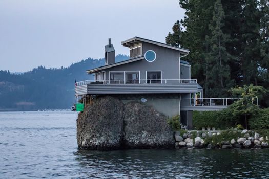 Coeur d'Alene, Idaho, USA-July 9, 2015: A house sits on the rocks overlooking Lake Coeur d'Alene at sunset in north Idaho. The area is a popular resort and tourist locale.