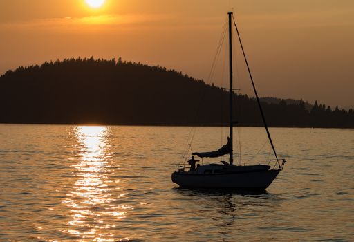 A skipper and his dog sails his boat during sunset on Lake Coeur d'Alene in Idaho in the summer.
Photo taken on: July 09th, 2015