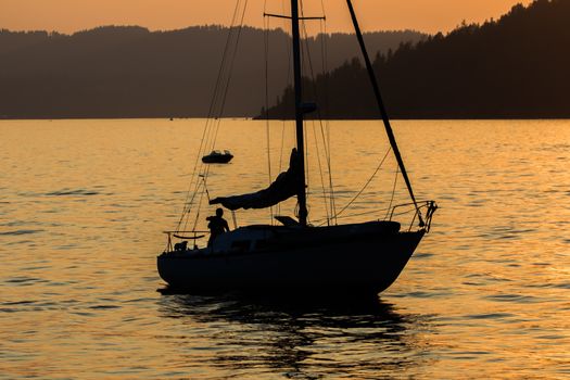 A skipper and his dog sails his boat during sunset on Lake Coeur d'Alene in Idaho in the summer.
Photo taken on: July 09th, 2015