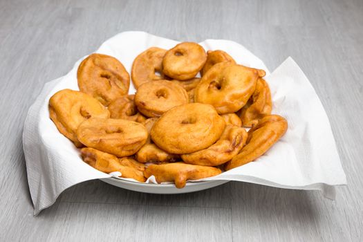 Many apple fritters with white napkins on scale