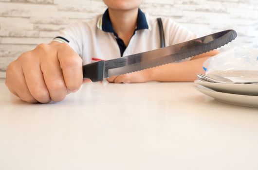 close up of a woman in casual clothes hold a knife