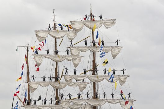 Few men standing up on the matt of sail boat, parade of Armada on the Seine, France