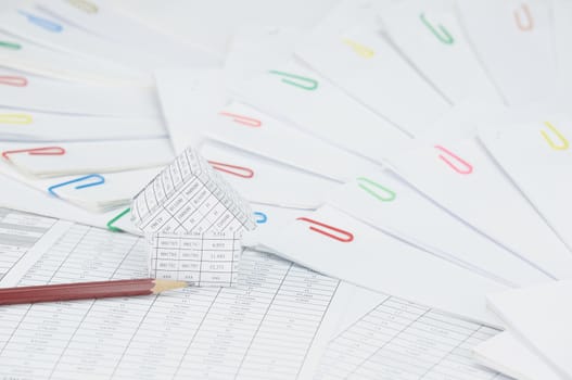 House with brown pencil on finance account have step of paperwork with colorful paperclip place curve as background.