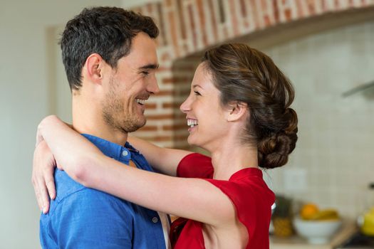 Close-up of romantic couple standing face to face and embracing each other in kitchen