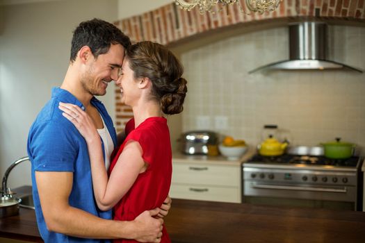 Romantic couple standing face to face and embracing each other in kitchen