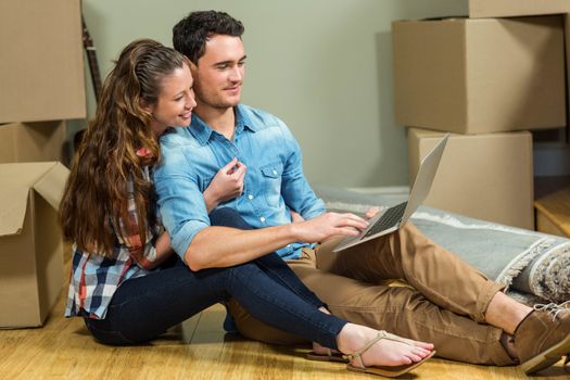 Young woman sitting on floor and using laptop in their new house