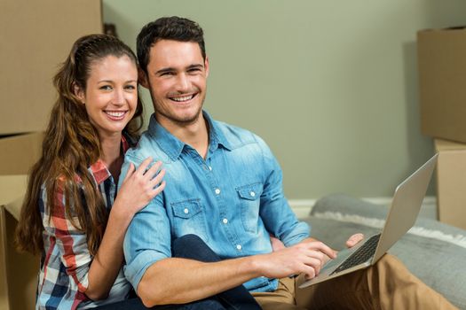 Young woman sitting on floor and using laptop in their new house