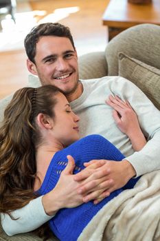 Romantic young couple cuddling on sofa in living room