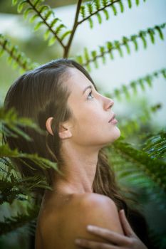 Beautiful woman standing outdoors against green plants