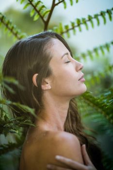 Beautiful woman standing outdoors against green plants