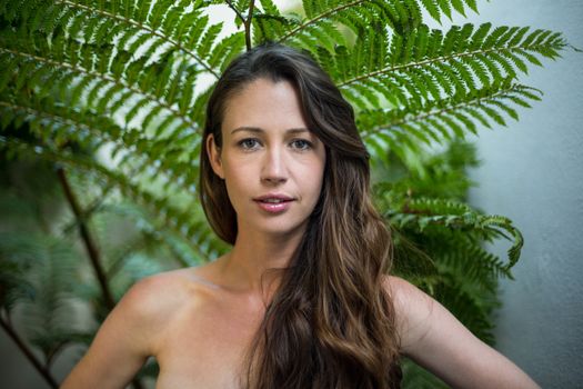 Portrait of beautiful woman standing outdoors against green plants