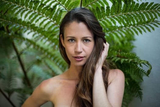 Portrait of beautiful woman standing outdoors against green plants