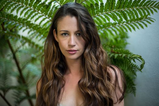 Portrait of beautiful woman standing outdoors against green plants