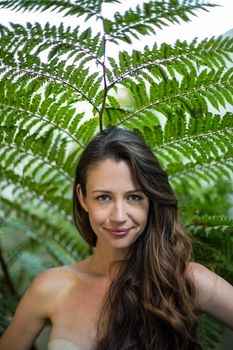 Portrait of beautiful woman standing outdoors against green plants