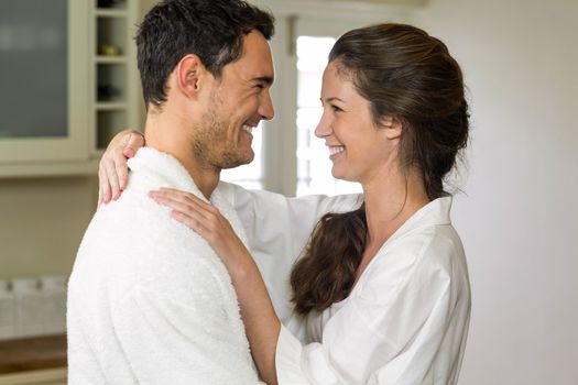 Romantic young couple in bathrobe embracing each other in kitchen