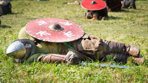Defeated warrior lying on the grass with his shield