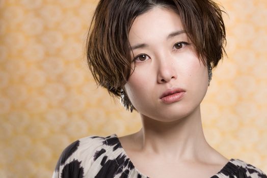 A portrait of a  young and beautiful Japanese woman shot on a yellow and white lace background.