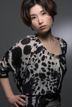 A portrait of a young and beautiful Japanese woman posed confidently shot on a dark background.