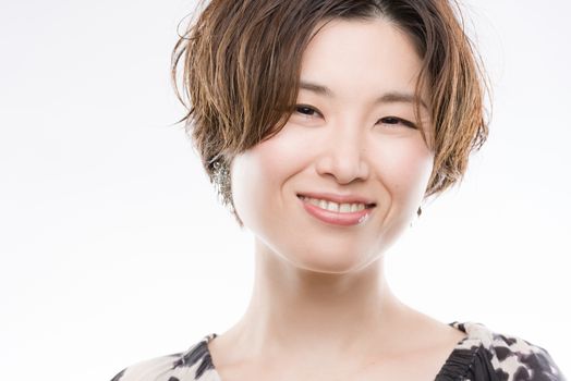 A high key headshot of a smiling, beautiful and young Japanese woman on a white background.