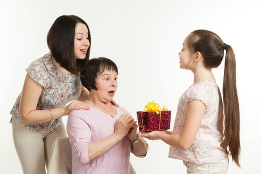 the daughter and the granddaughter give a gift to the grandmother