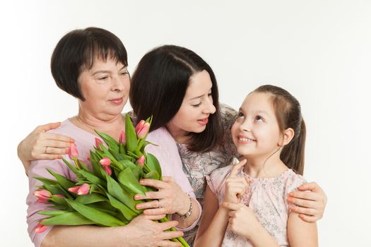 the mature woman, the young woman and the girl stand nearby and hold a bouquet of tulips