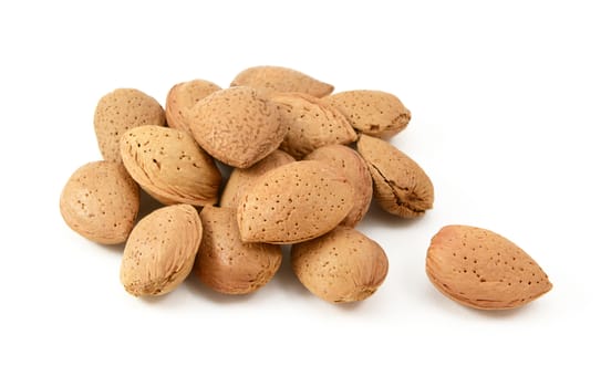 Small heap of whole almonds in shells, a single nut lies separate from the main pile, isolated on a white background