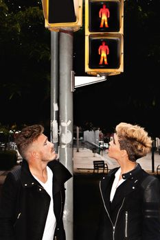 Trendy young couple looking at the traffic light in the middle of the street. Urban fashion photography. Vertical image.